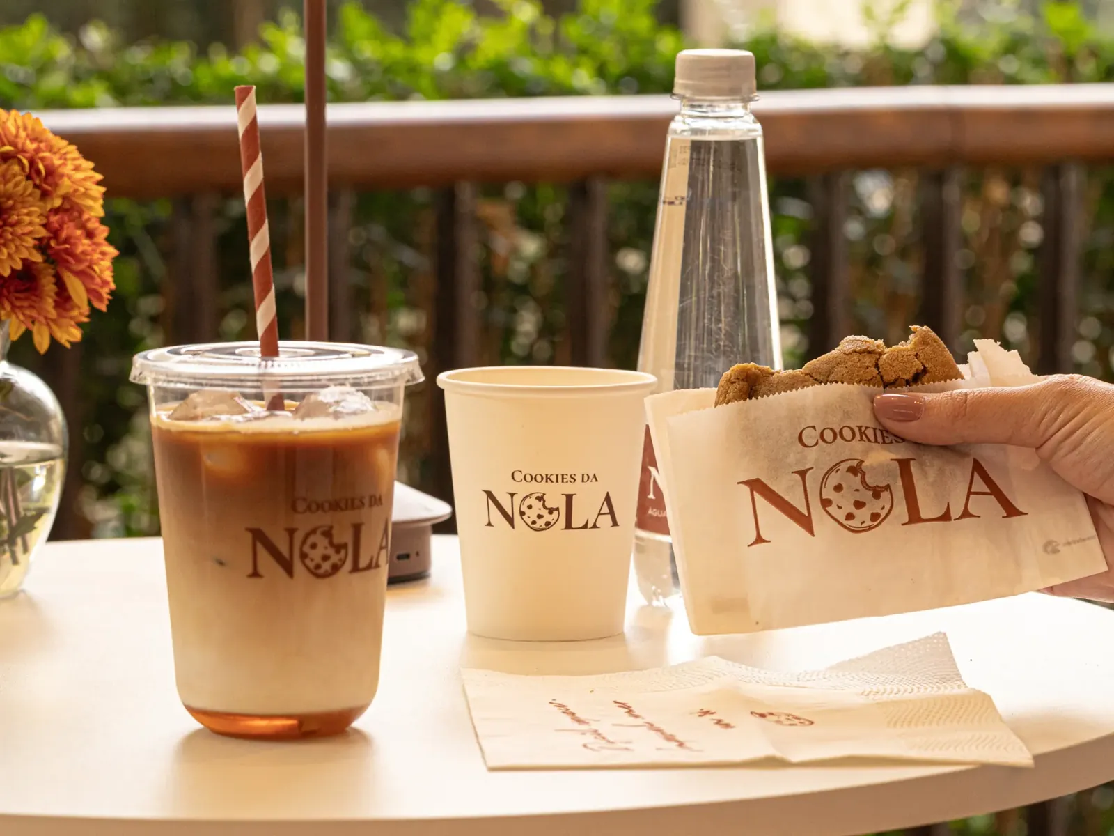 Cookie artesanal e café gelado servidos lado a lado em uma mesa da loja Cookies da Nola